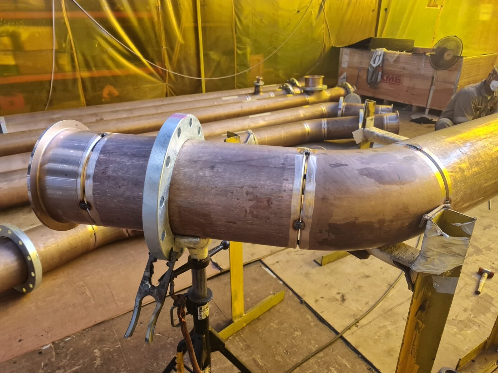 Large bore bend and flange set up on stands inside a welding habitat