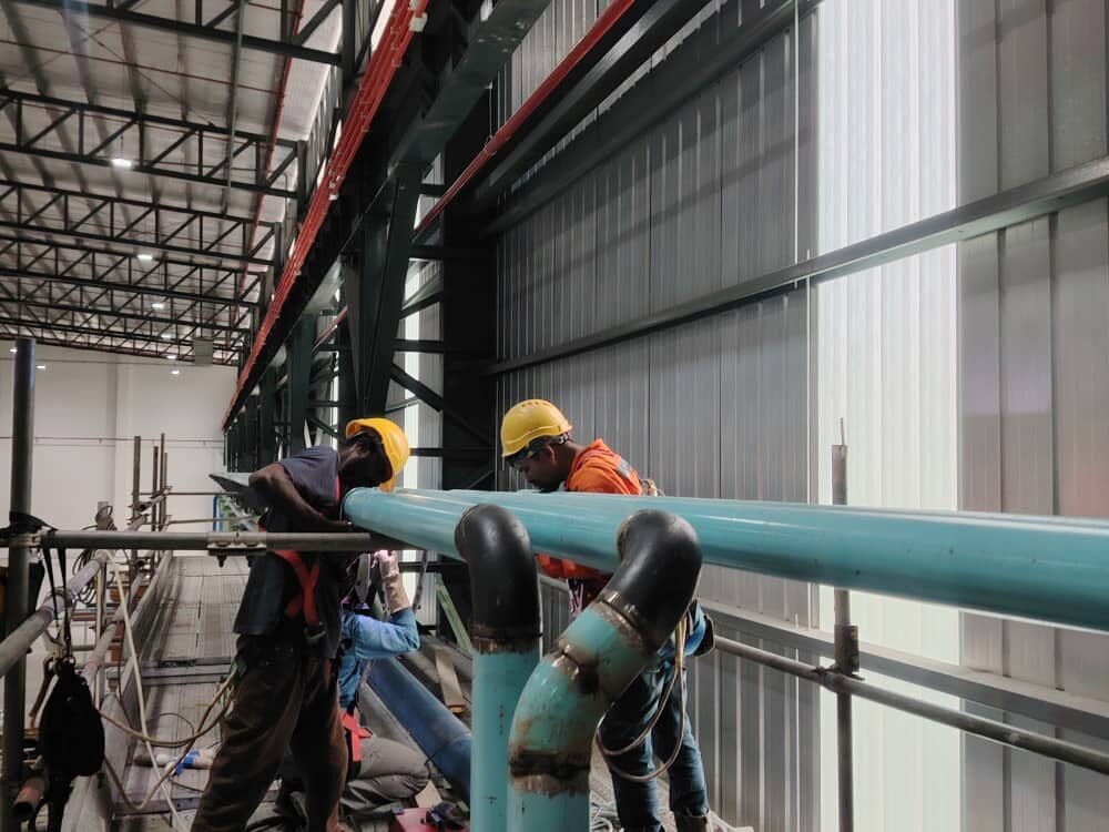 Crew welding elbows into a high level pipe run from access scaffold