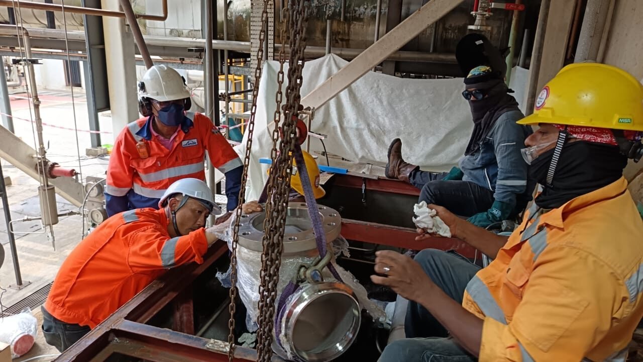 Crew lifting a flanged pipe spool into position under supervision