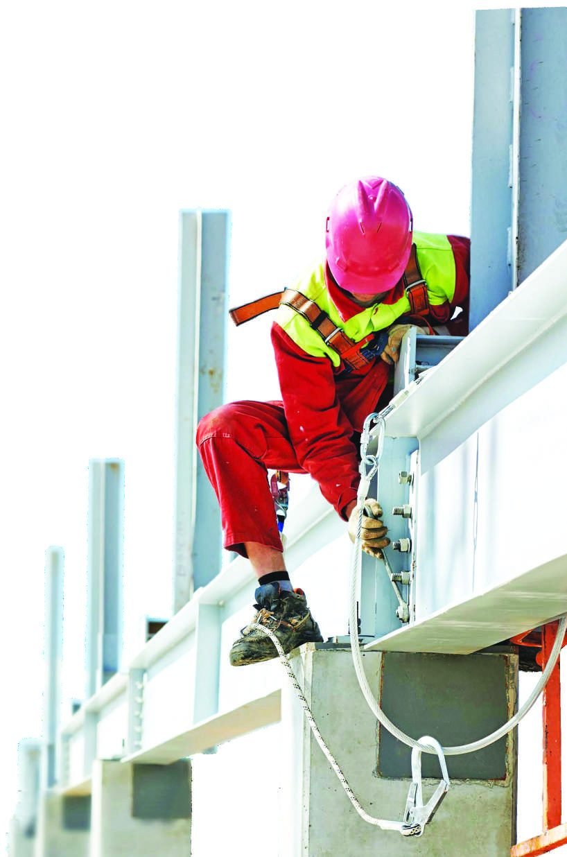 Worker in full harness and PPE working at height on structural steel