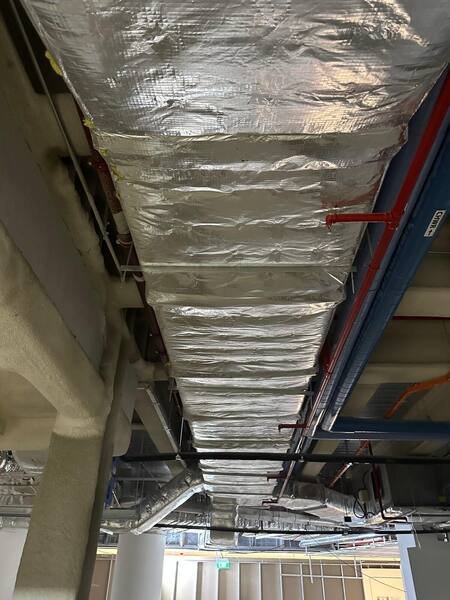 Foil-clad insulated duct main supported from the slab